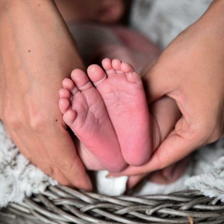 Femme qui tient des pieds de bébé dans ses mains
